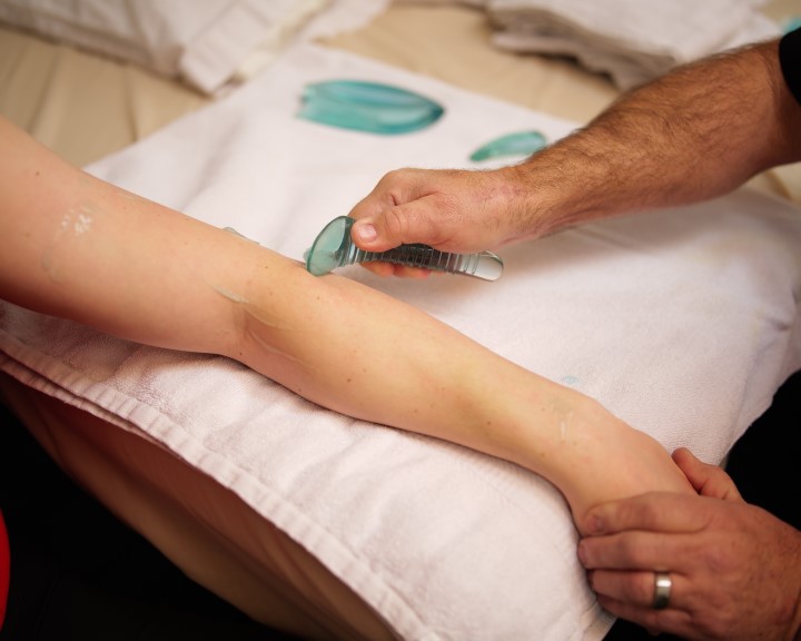 image of a person's arm being treated by a provider using a massage tool